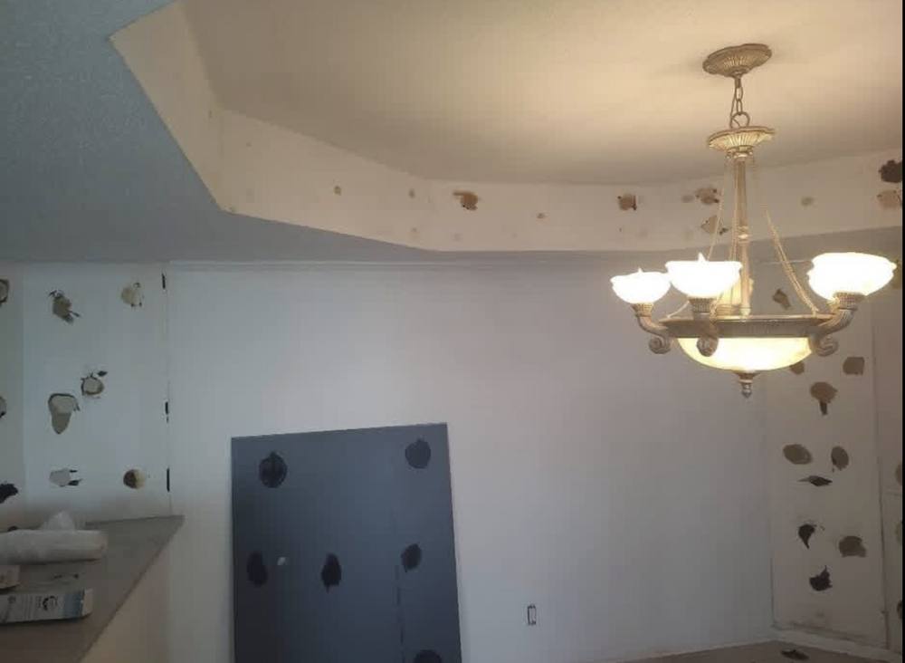 Condo dining room before, with wall repairs needed